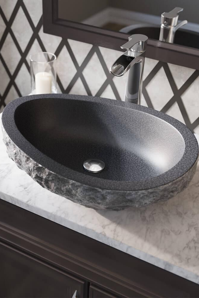 Vasque ovale en pierre noire avec robinetterie moderne dans une salle de bains.