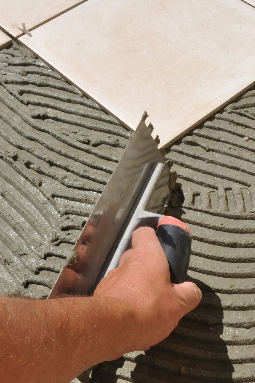Pour la pose de carrelage, utiliser une truelle crantée pour appliquer le mortier sur une surface en préparation.