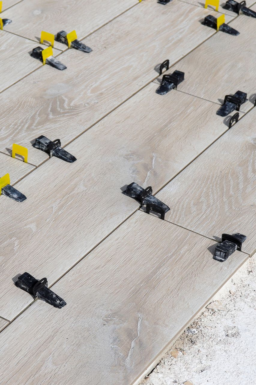 Pose des carreaux à l'aide de clips et de cales de nivellement pour un espacement régulier.