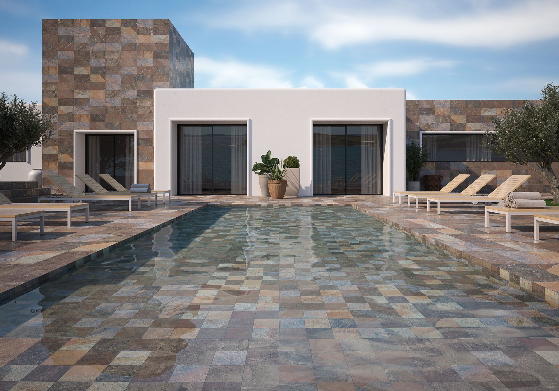 Villa avec une piscine rectangulaire. Chaises longues et plantes en pot. Bâtiment aux murs de pierre blancs.