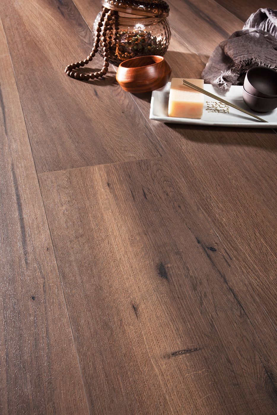 Sol en bois foncé avec des éléments de spa : pot, perles, savon, bol, serviette.