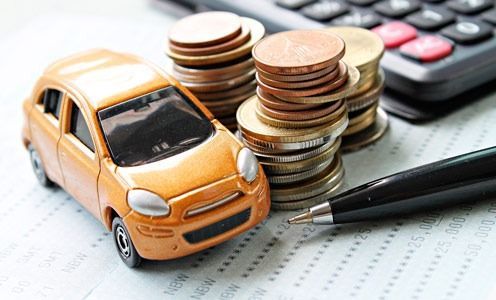 Un coche de juguete está encima de una pila de monedas al lado de un bolígrafo y una calculadora.