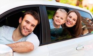 Una familia está sentada en un coche mirando por la ventana.
