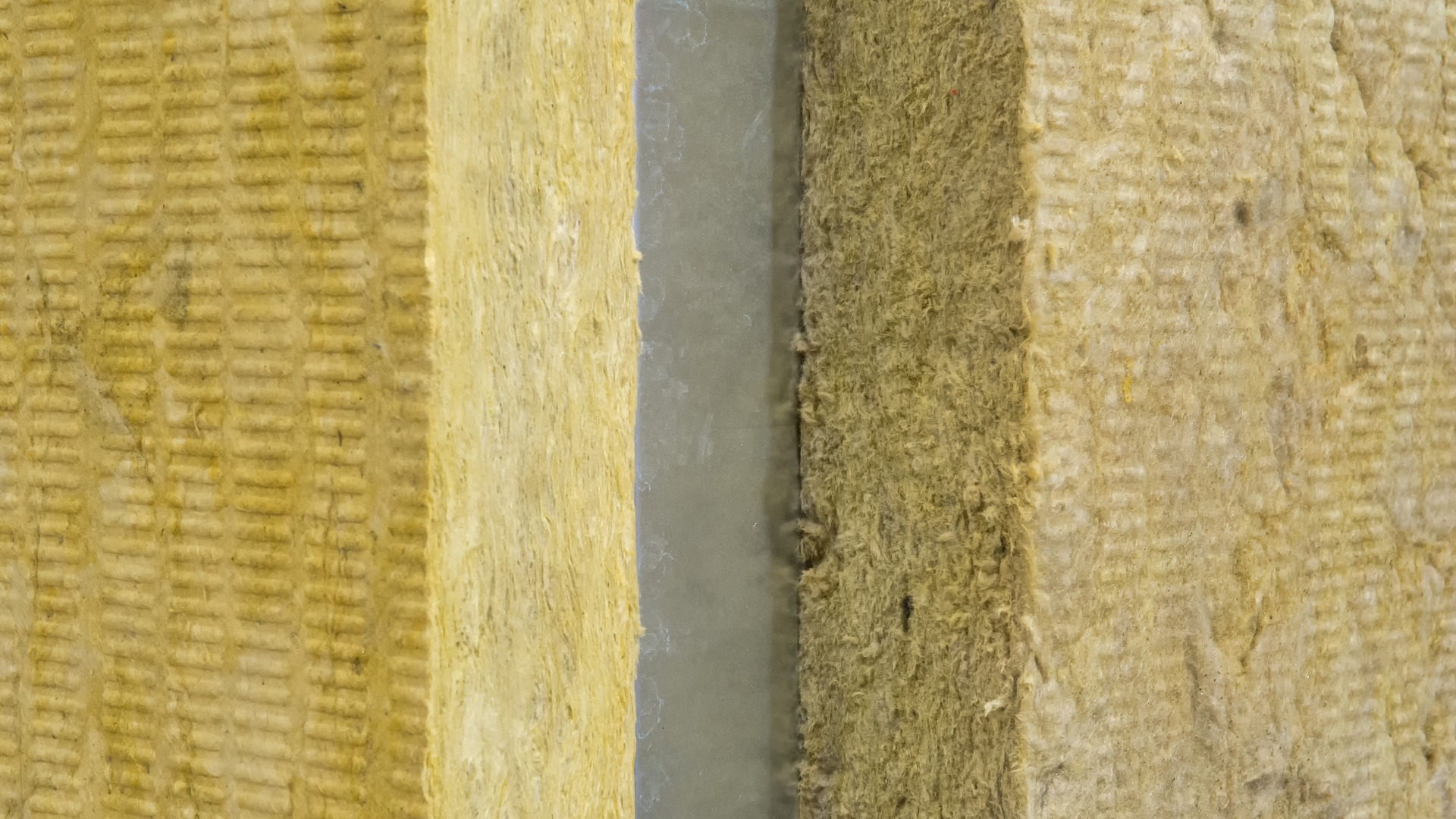 Gros plan sur des blocs d'isolation en laine minérale, avec un mastic gris entre eux.