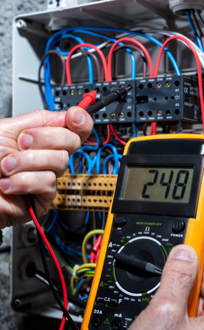 Un électricien teste la tension dans un tableau électrique avec un multimètre .