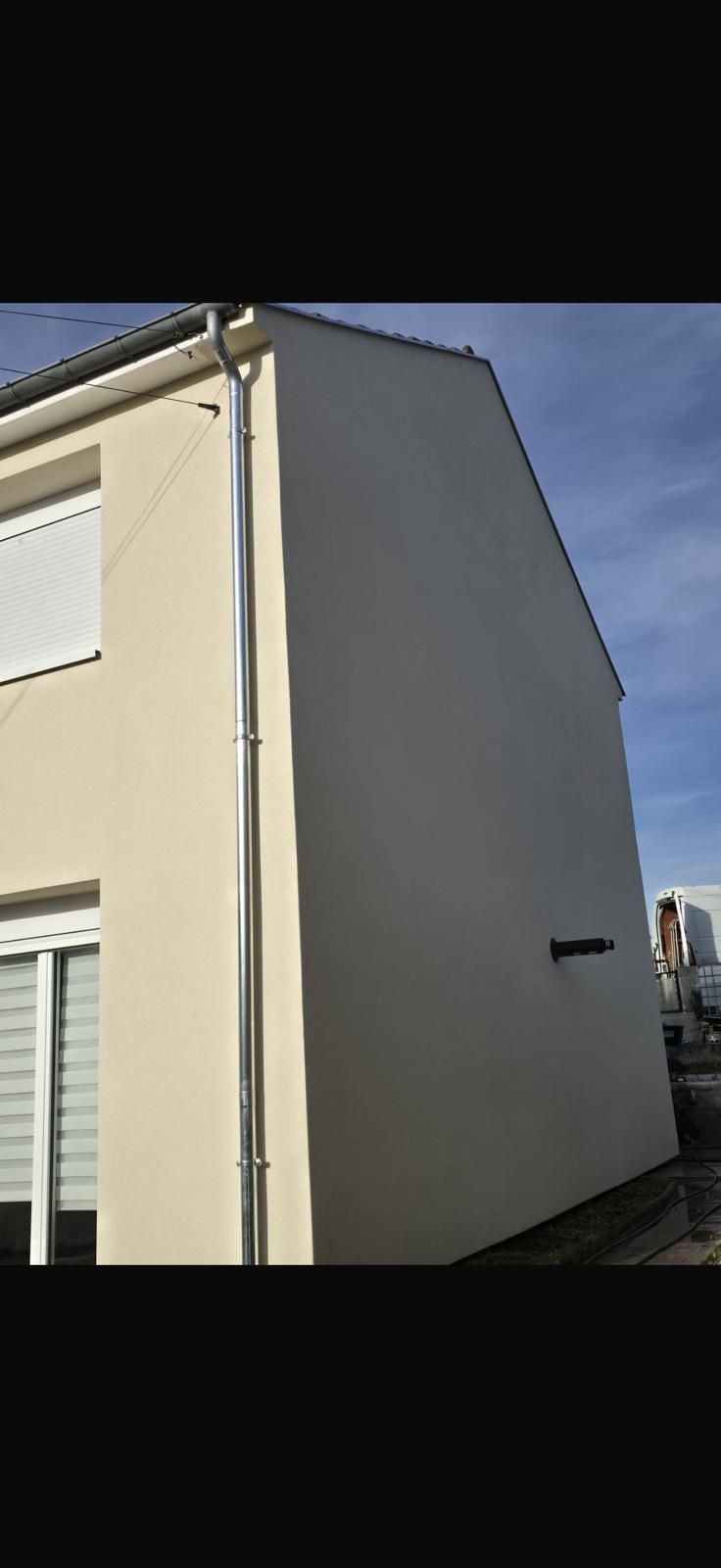 Immeuble beige à plusieurs étages avec balcons noirs et grandes vitrines donnant sur un trottoir.