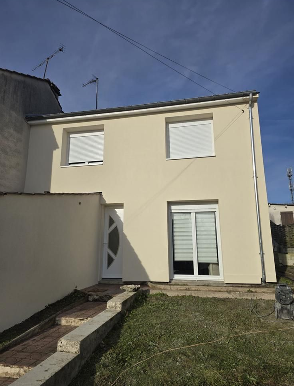 Personne versant de la peinture blanche d'un pot dans un bac à peinture, portant des gants de travail et un jean.