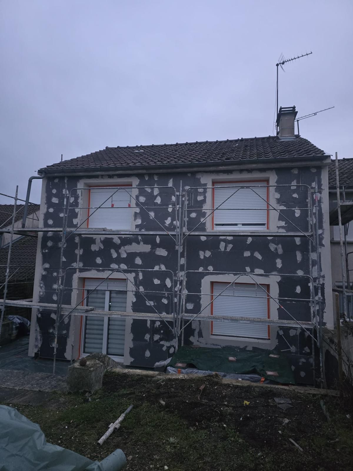 Façade du bâtiment en cours de rénovation ; échafaudages, bétonnières et façade abîmée par les intempéries.