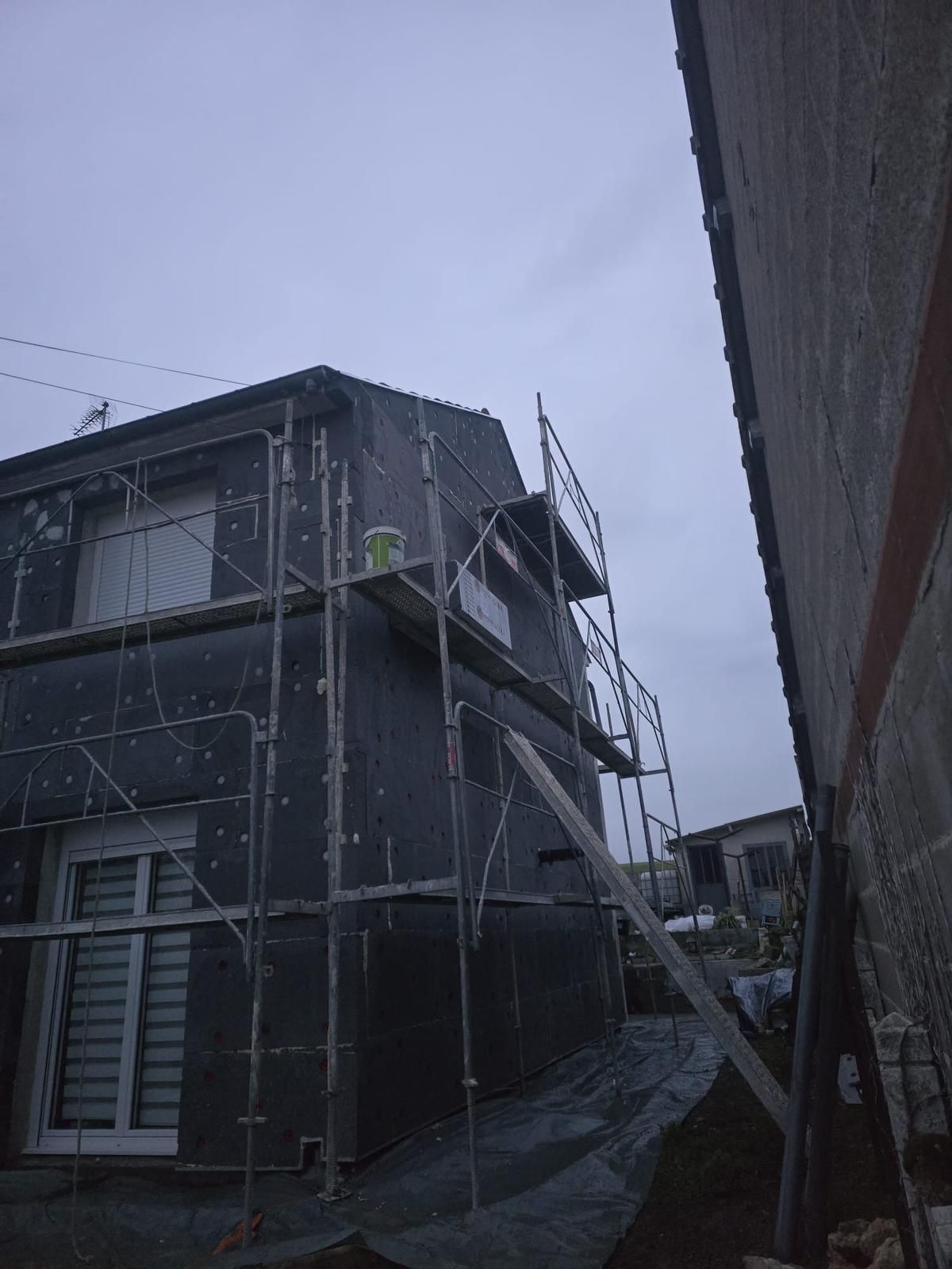 Bâtiment en rénovation avec échafaudages et matériaux de construction sur le trottoir.