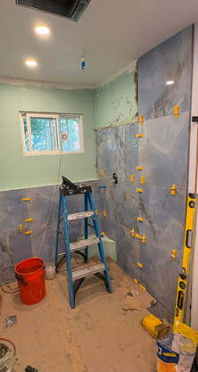 Rénovation de la salle de bain en cours. Pose de carrelage mural bleu avec croisillons jaunes.