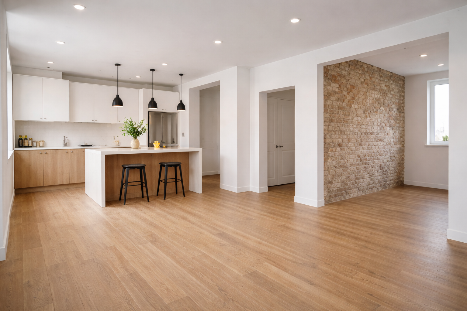 Cuisine et séjour modernes à aire ouverte avec parquet, armoires blanches et mur d'accent en pierre.