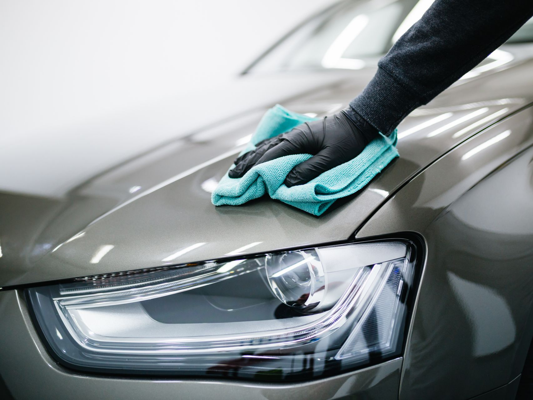 Un professionnel qui essuit la carrosserie d'une voiture à l'aide d'un chiffon microfibre.
