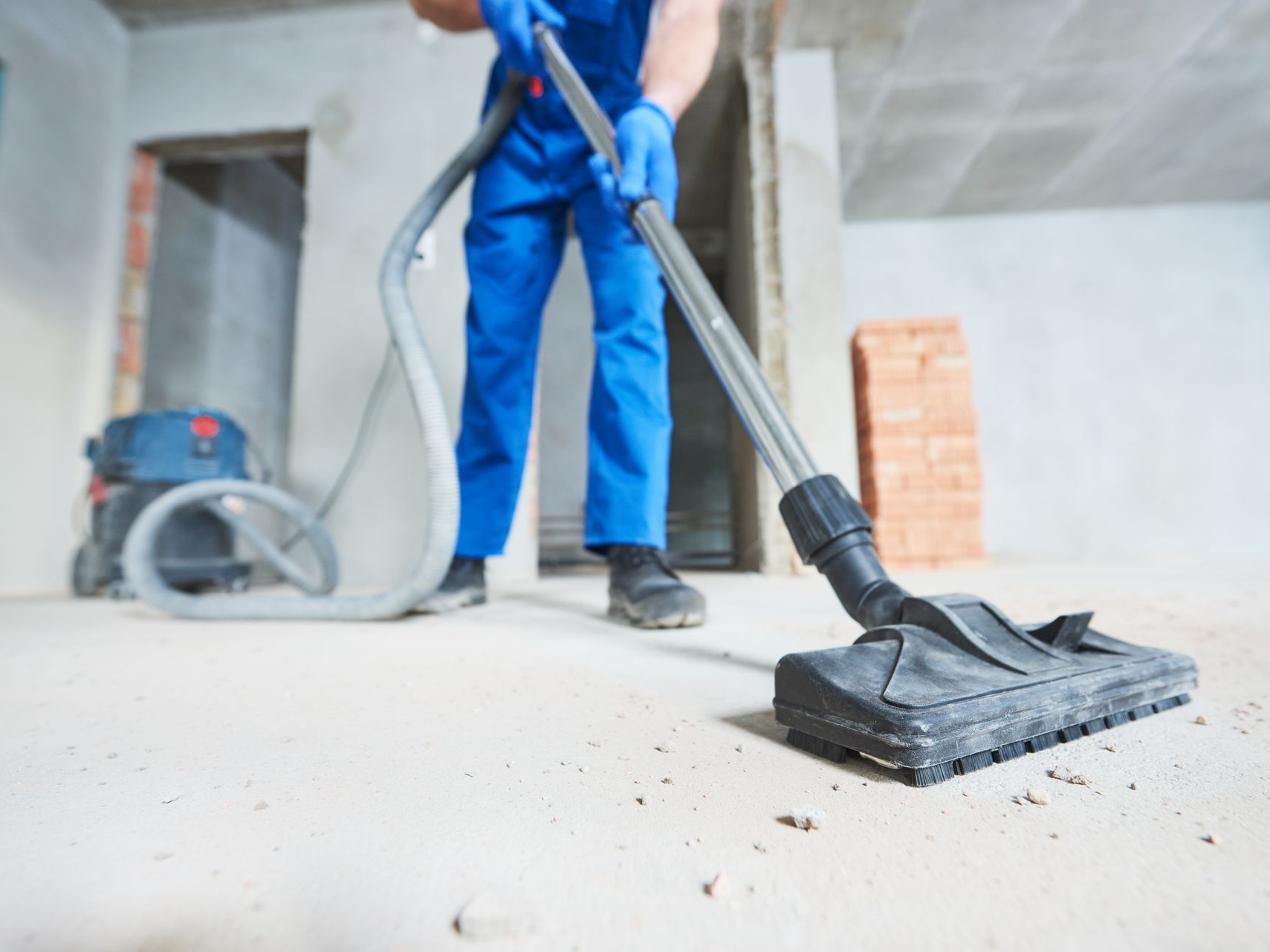 Un professionnel qui aspire des gravats au sol à l'aide d'un aspirateur professionnel.