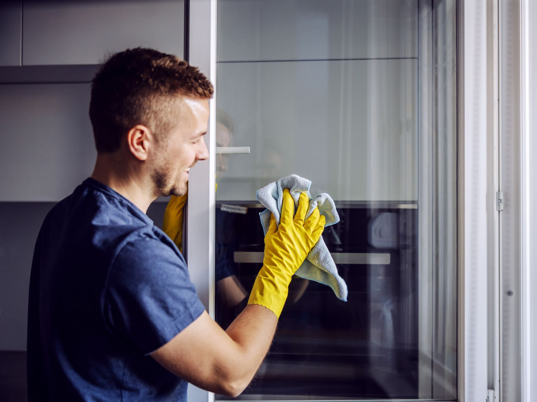 Un agent de nettoyage qui nettoie une vitre à l'aide d'un chiffon.