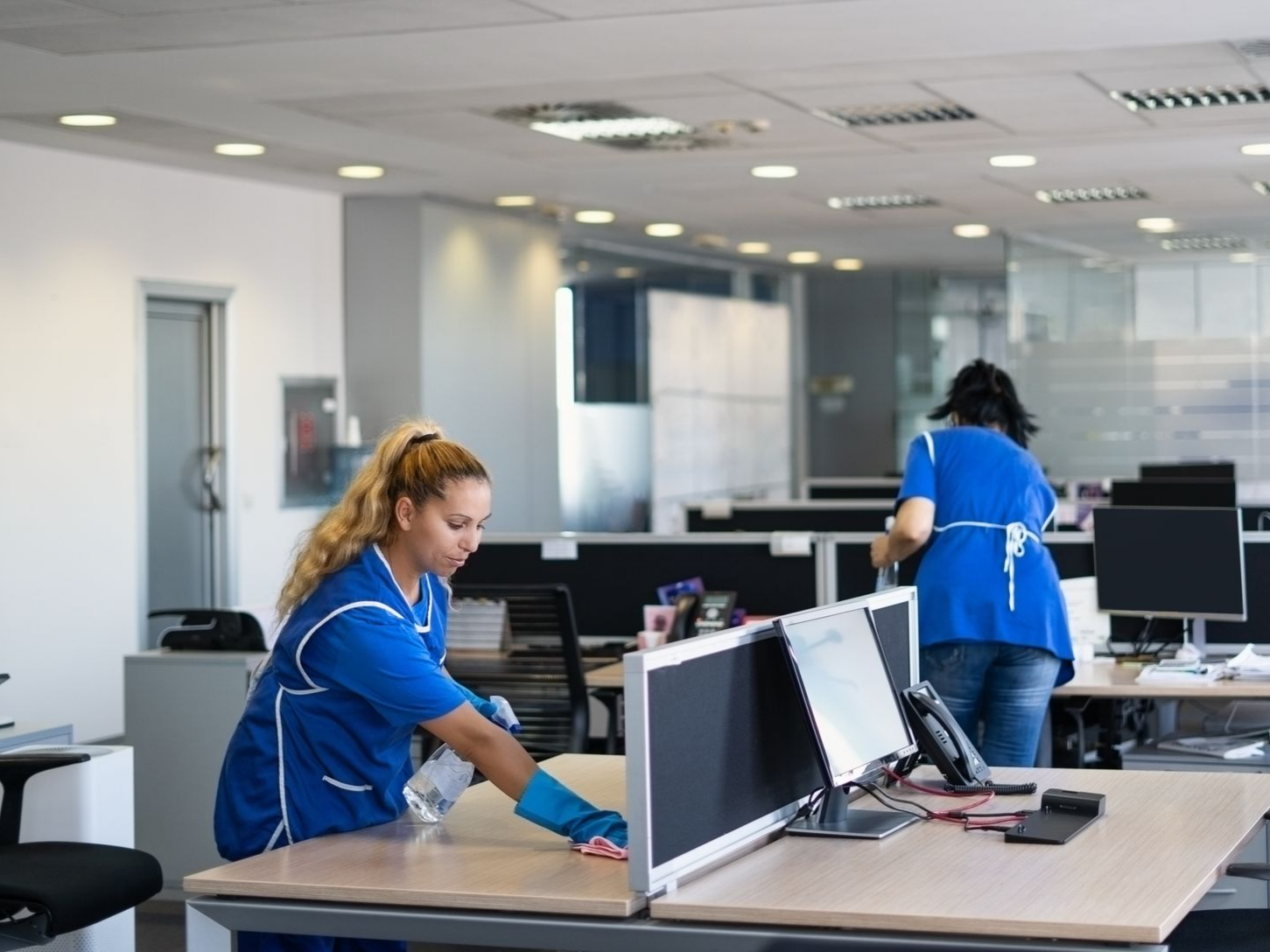 Des agents de nettoyage qui nettoient des bureaux dans un open-space.