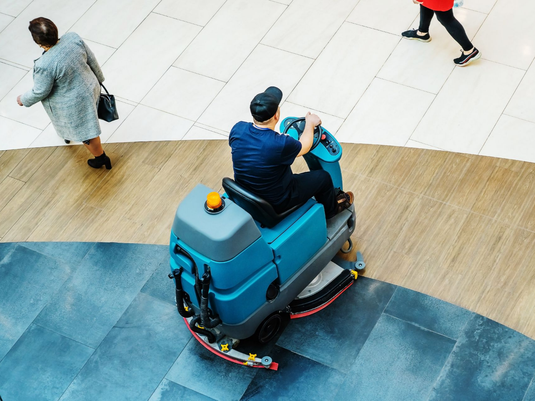 Un professionnel assis sur une autolaveuse dans une galerie commerciale.