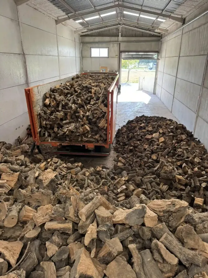 Dentro de un almacén, un carro naranja cargado y un montón de corcho marrón astillado.
