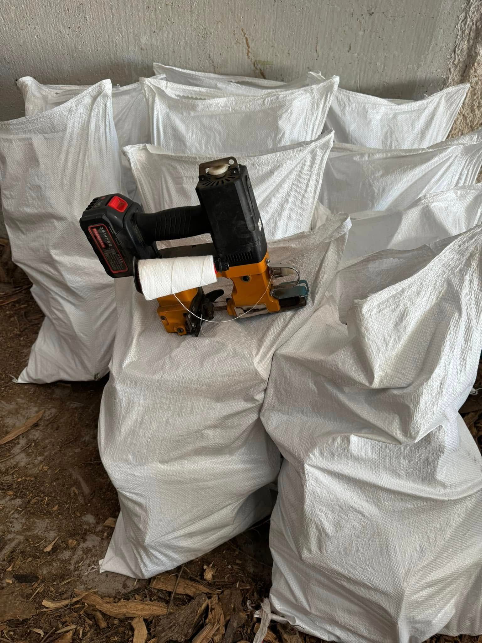 Una grapadora inalámbrica descansa sobre varios sacos de arpillera blancos en un área de almacenamiento.