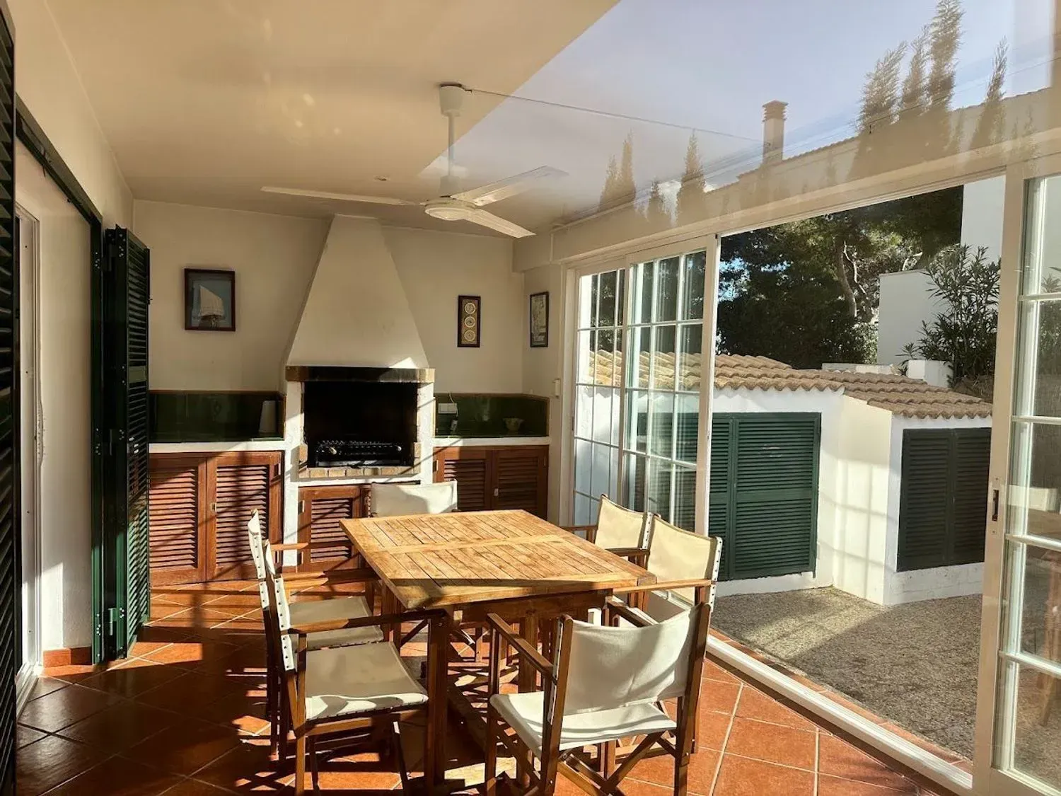 Cocina y comedor modernos y luminosos con armarios blancos, mesa de madera, sillas azules y lámparas colgantes.