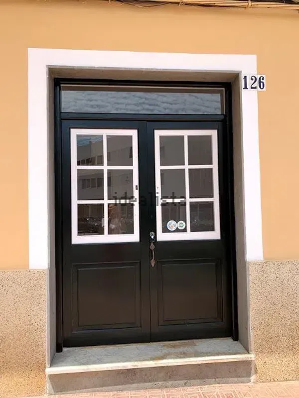 Puertas dobles negras con ventanas de paneles blancos en un edificio color melocotón, número 126 sobre el lado derecho.