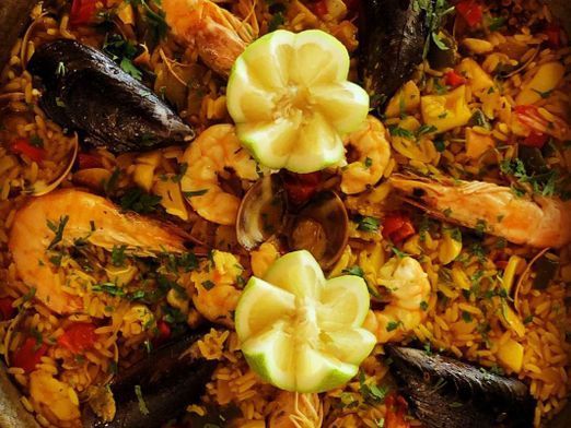 Un primer plano de una paella con camarones, mejillones y arroz.