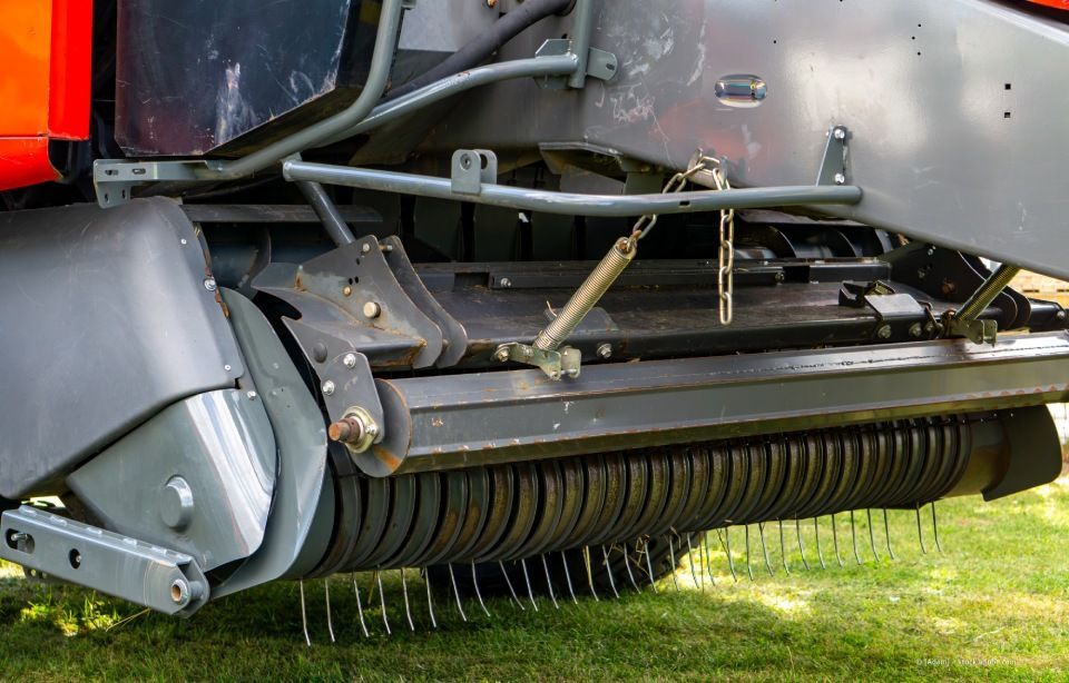 Ein roter Traktor fährt unter einem teilweise bewölkten Himmel durch ein abgeerntetes Feld.