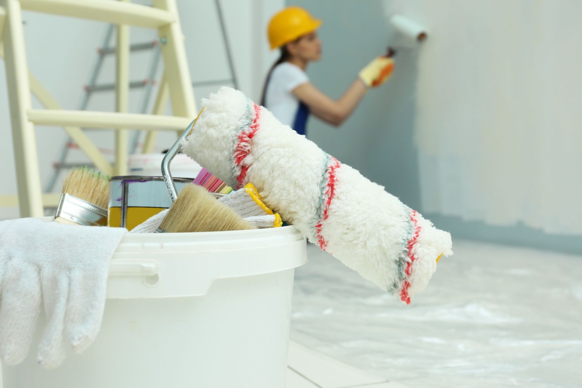 Una mujer está pintando una pared con un rodillo de pintura.