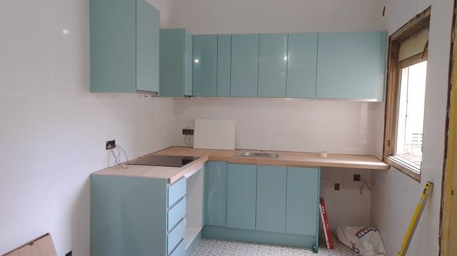 Una cocina con gabinetes azules y una cinta métrica amarilla.