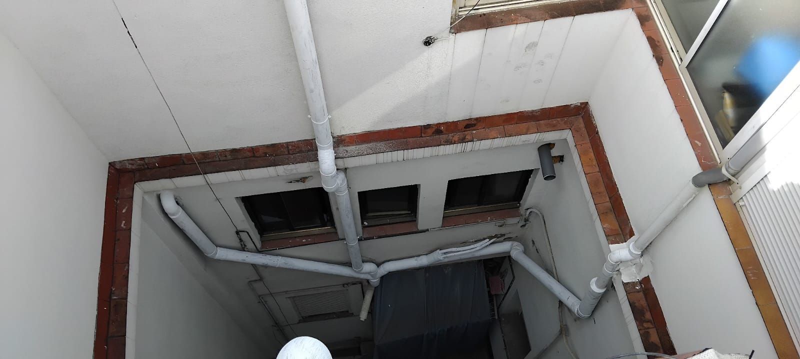 Un hombre con un casco blanco mira hacia un agujero en la pared.