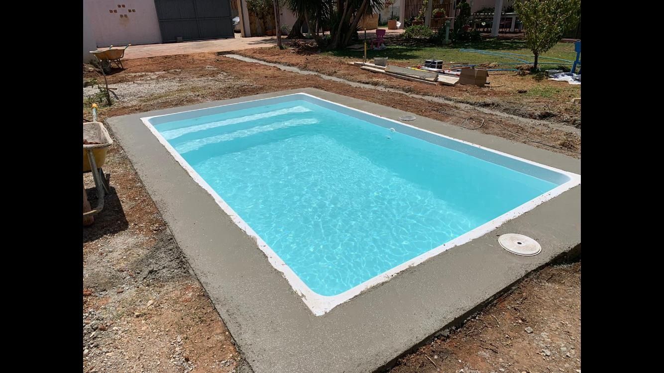 Una pequeña piscina está situada encima de un patio de hormigón.