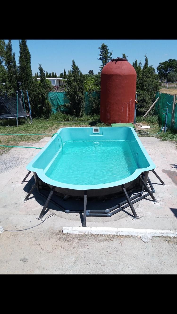 Una piscina verde está al lado de un tanque de agua rojo.