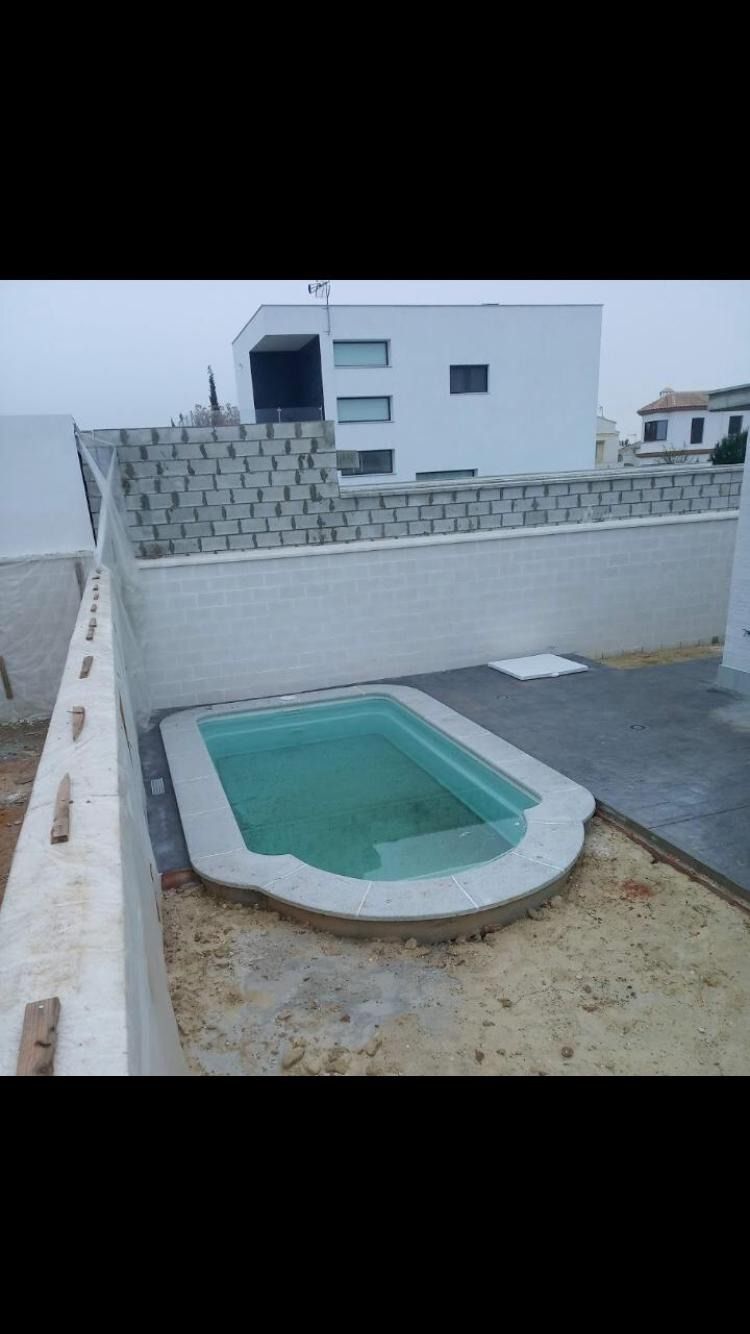 Una pequeña piscina está rodeada por una valla y un edificio.