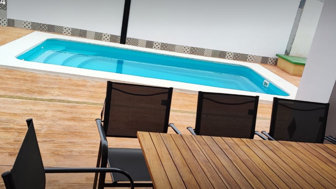 Una mesa y sillas frente a una piscina.
