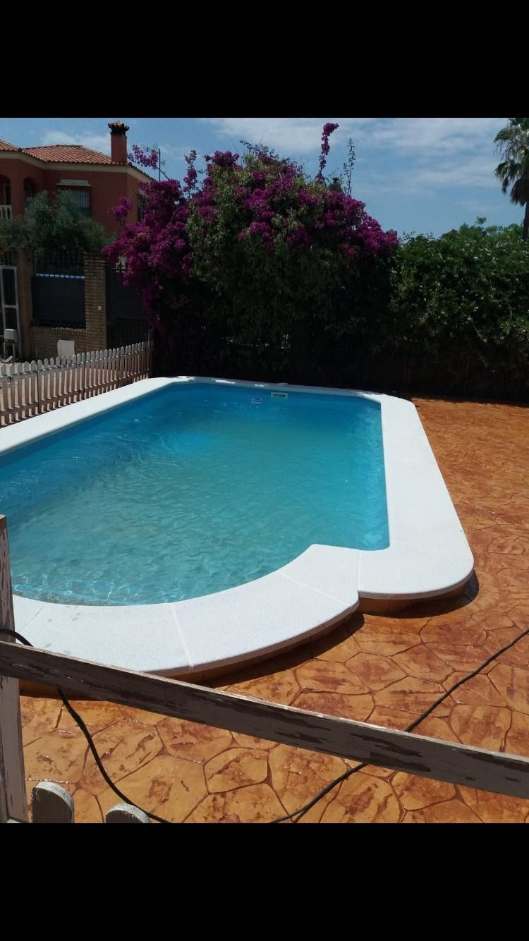 Una gran piscina con flores violetas al fondo.