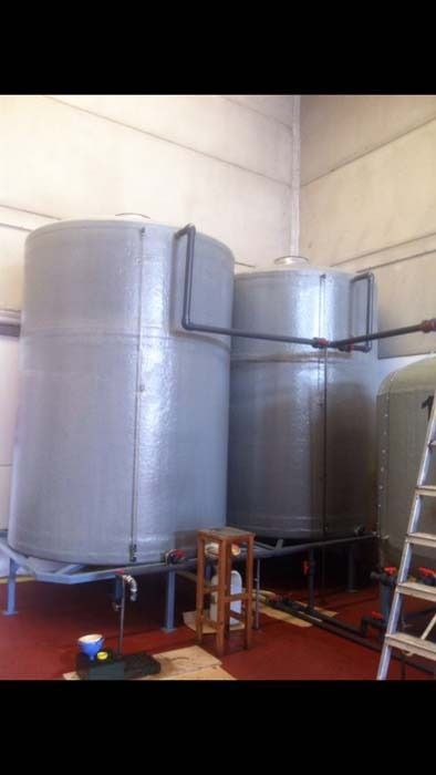 Dos grandes tanques de metal están sentados en una habitación al lado de una escalera.