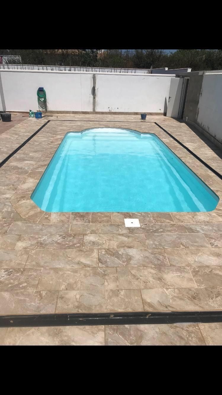 Una gran piscina se encuentra encima de un patio embaldosado.