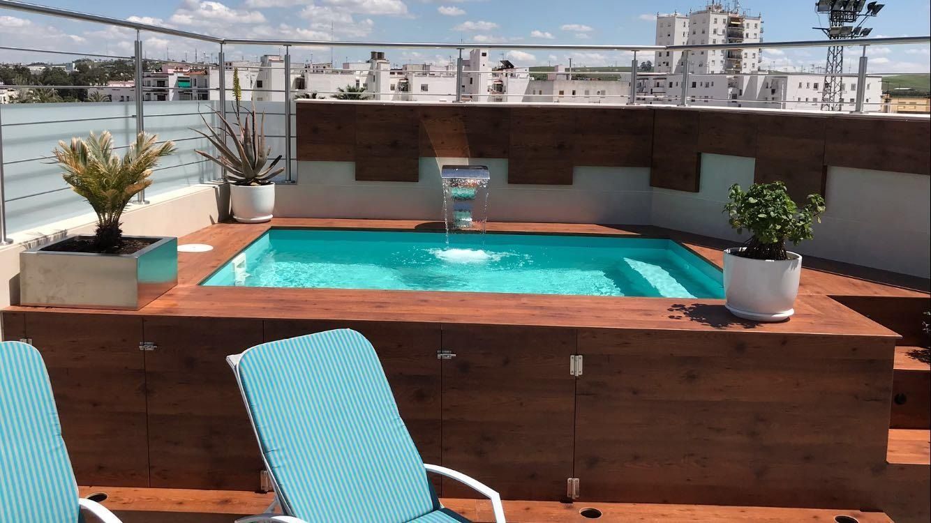 Una piscina en la azotea con sillas y plantas.