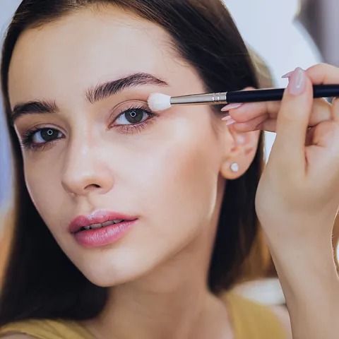 Una mujer se está aplicando maquillaje en los ojos con un pincel.