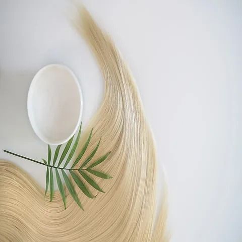Hay un recipiente con champú y una hoja de palma en el cabello.