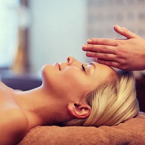 Una mujer está recibiendo un masaje de cabeza en un spa.