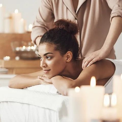 Una mujer está recibiendo un masaje en un spa con velas de fondo.
