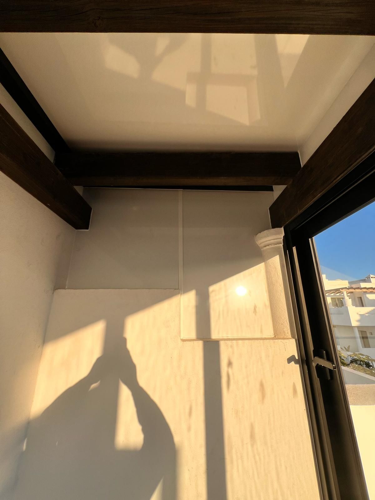 Una sombra de una persona se proyecta sobre una pared frente a una ventana.