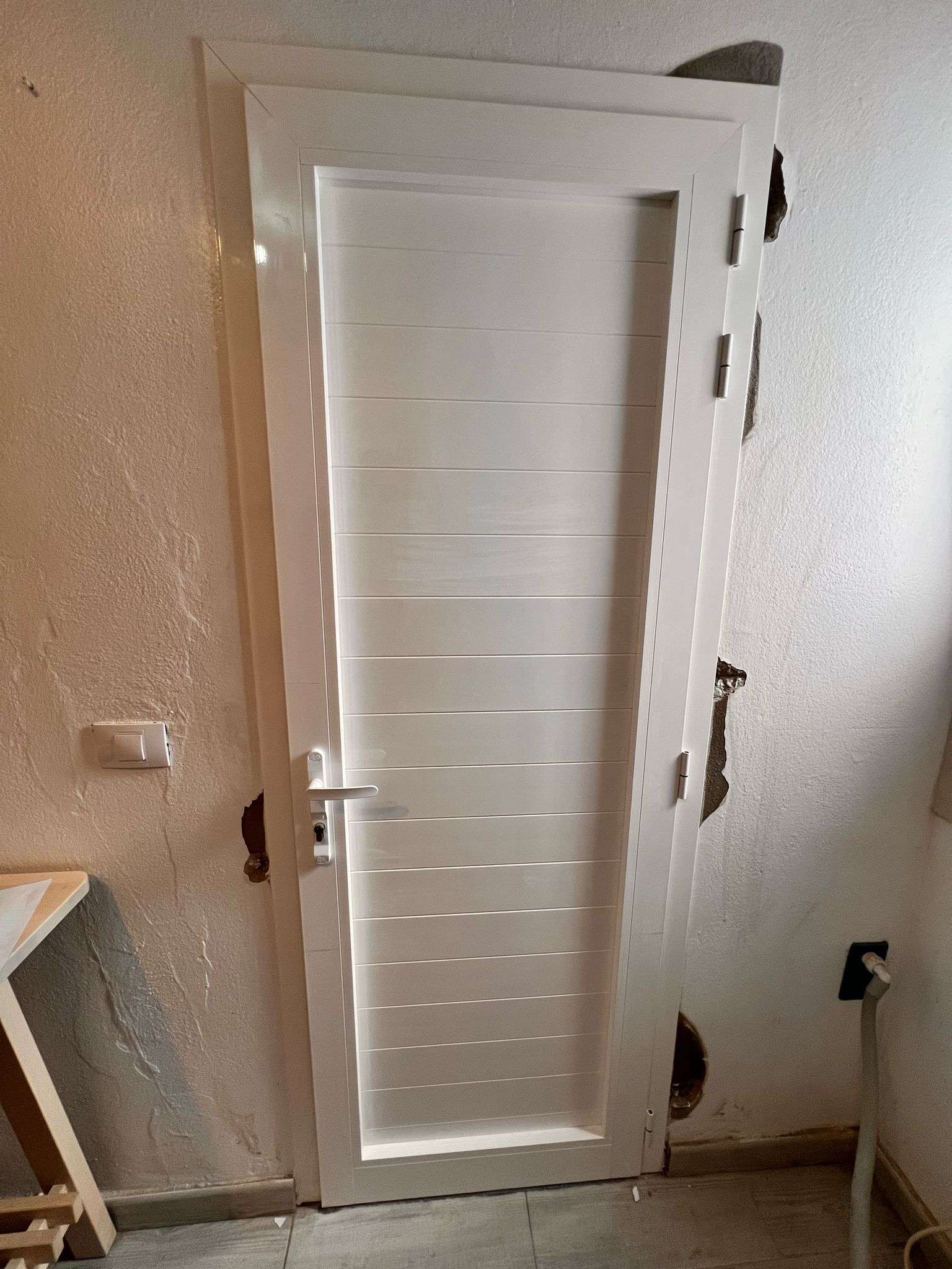 Una puerta blanca está en una habitación al lado de una pared.