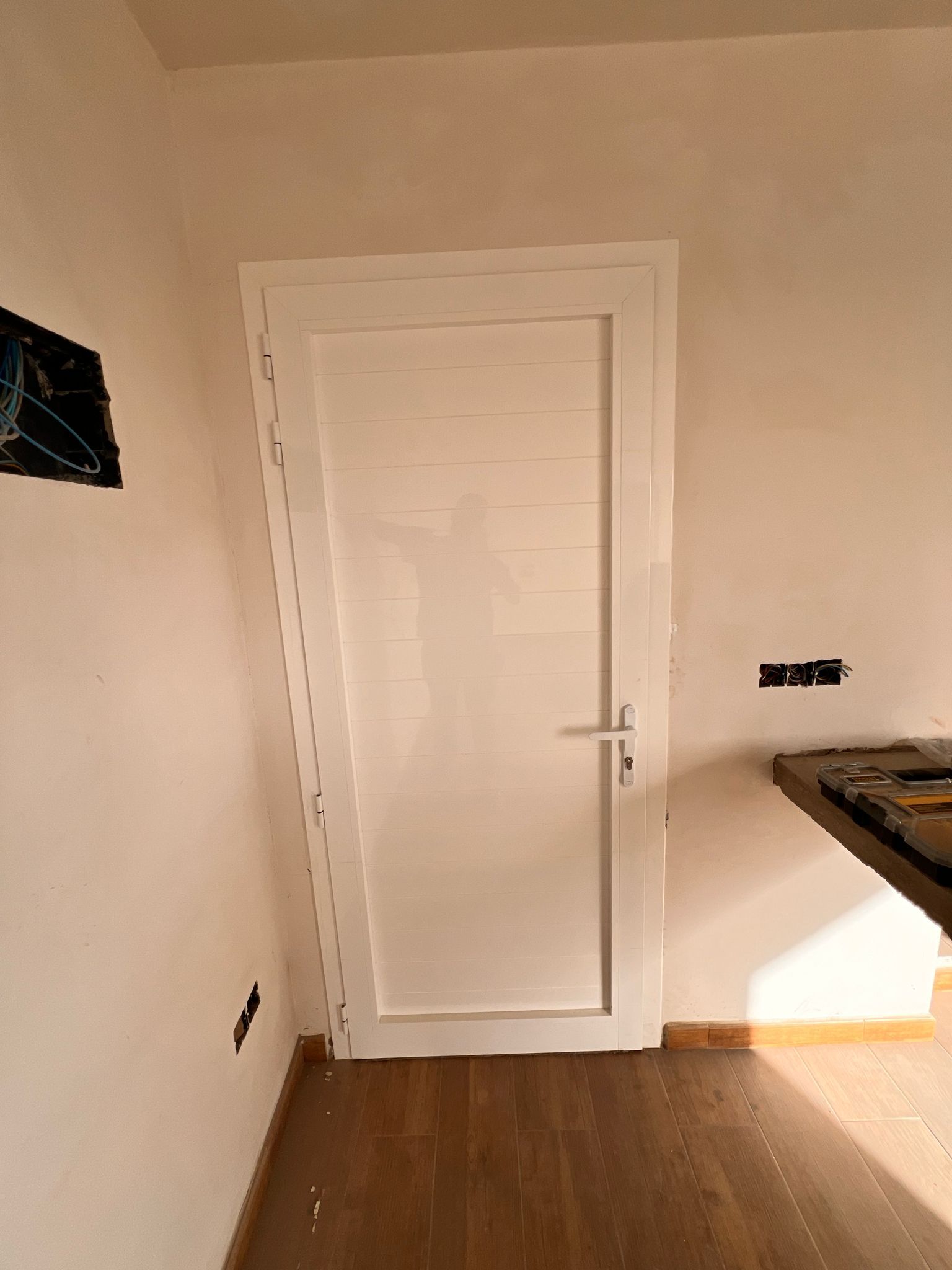 Una puerta blanca está en una habitación con piso de madera.