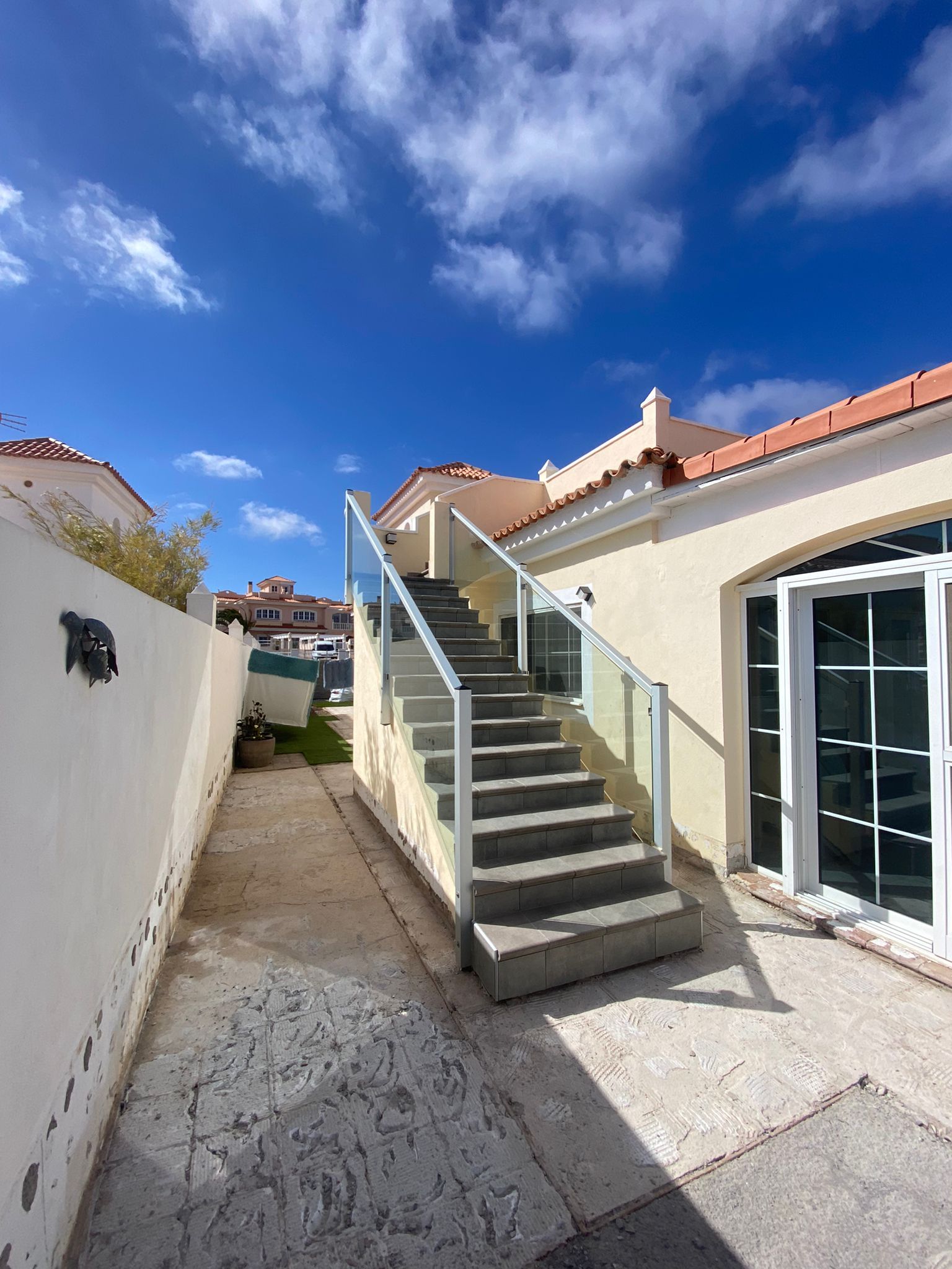 Escaleras que conducen a una casa con barandilla de cristal.