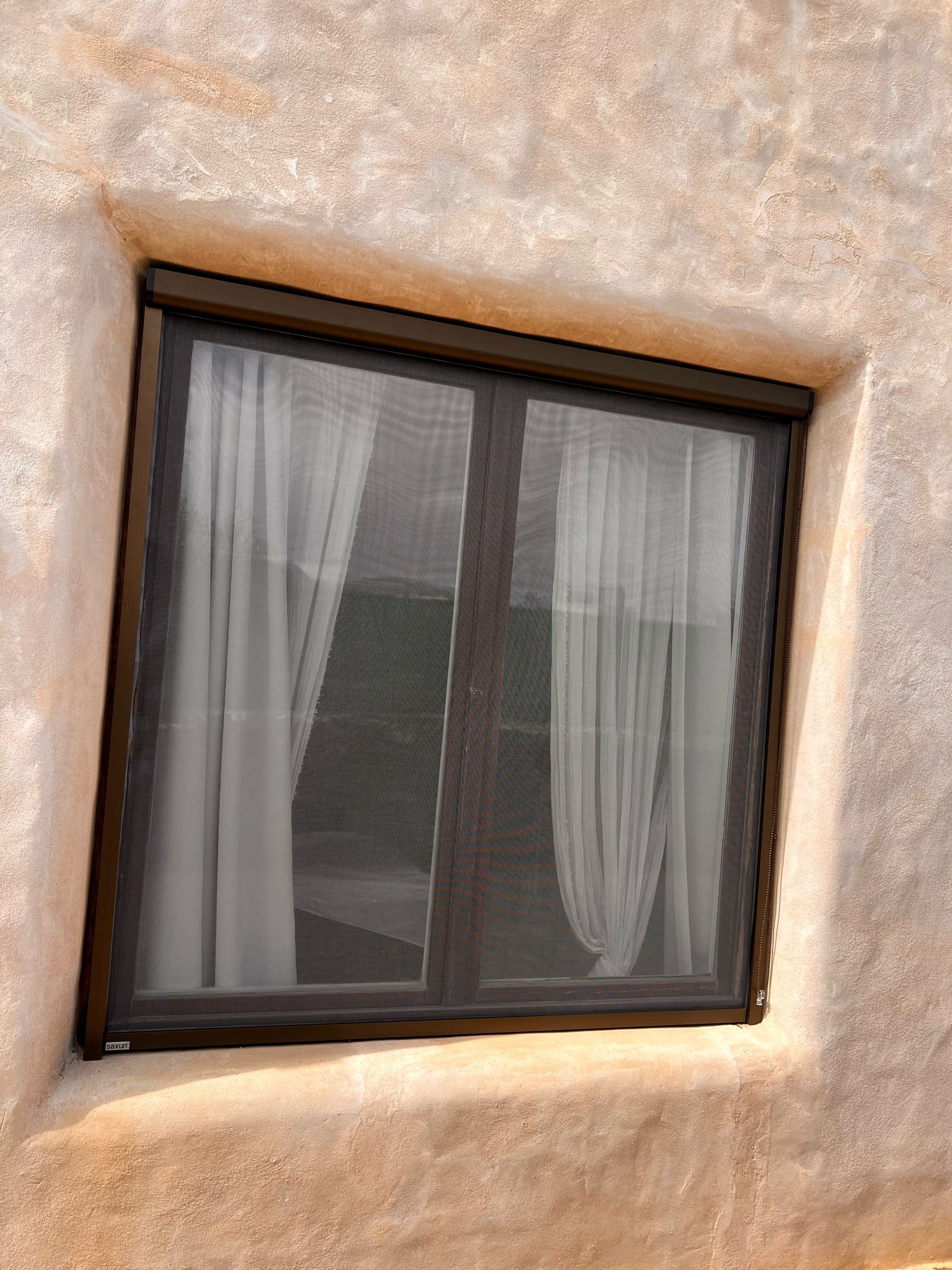 Una ventana con una mosquitera está en el costado de un edificio.