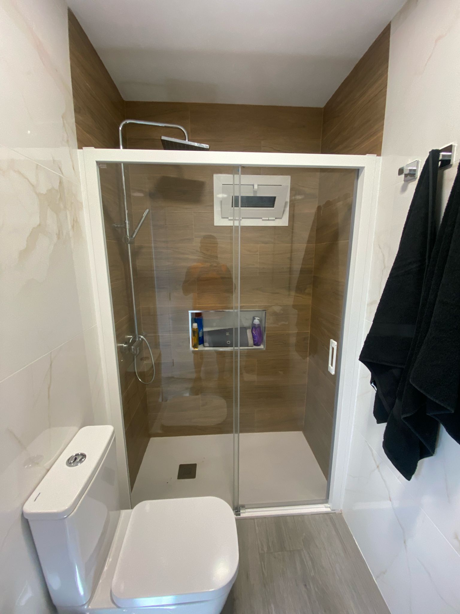 Un baño con inodoro, ducha y puerta corrediza de cristal.