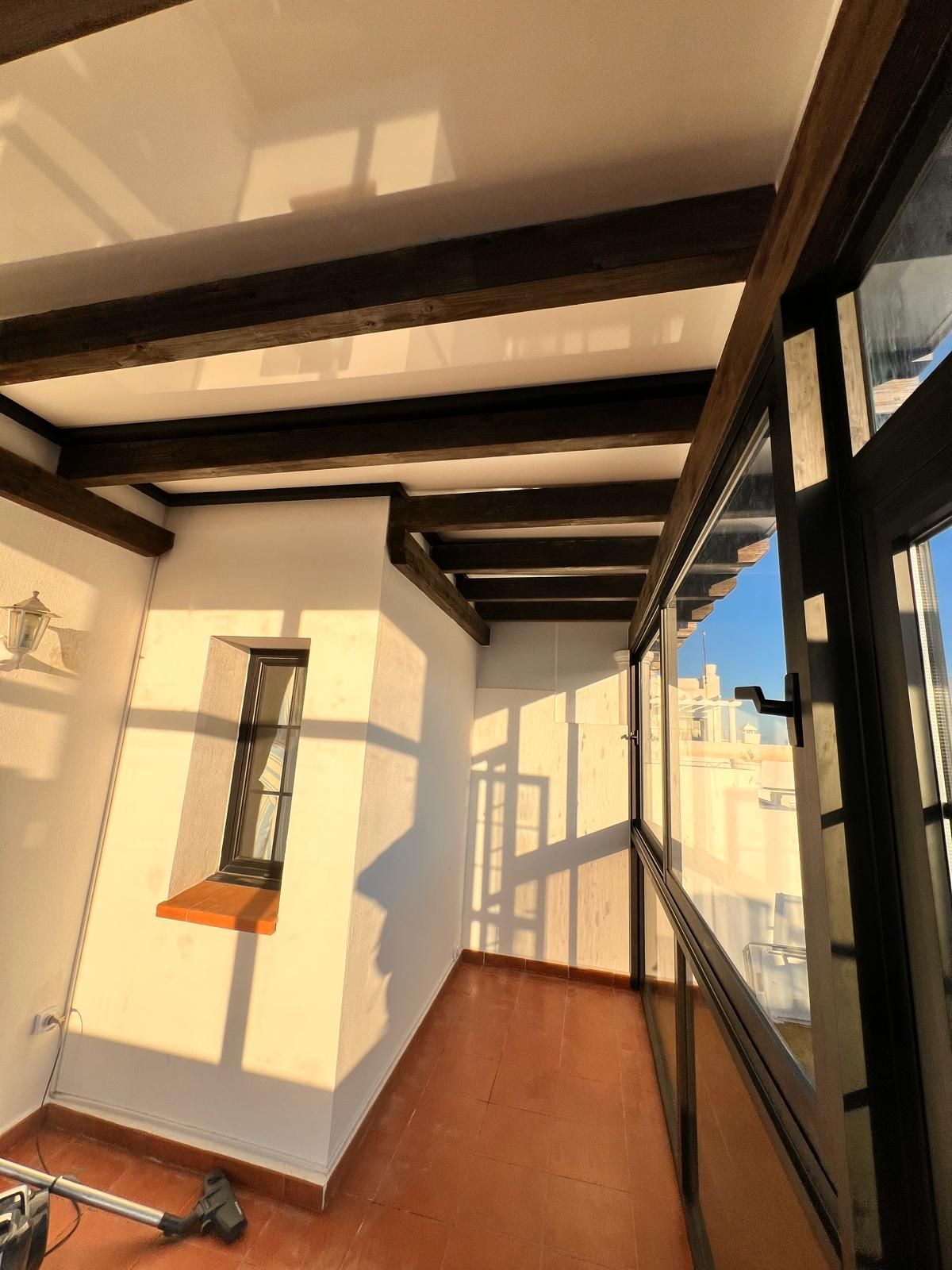 Una habitación con muchas ventanas y una aspiradora en el suelo.