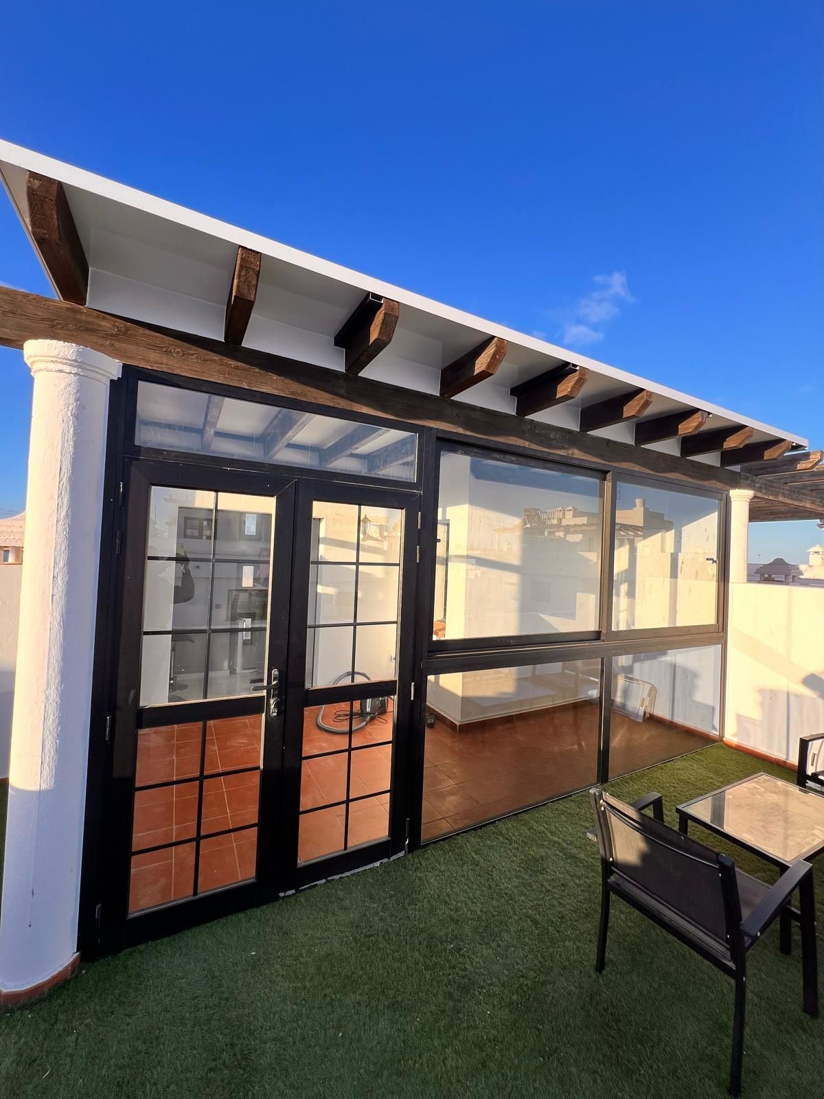 Un patio con una mesa y sillas bajo una pérgola.