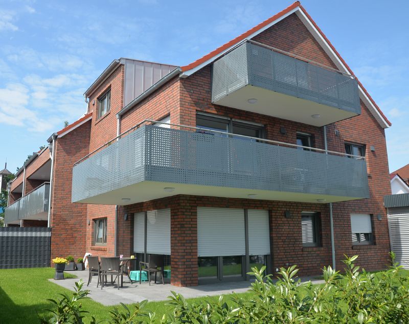 Ein Backsteinhaus mit Balkon und Rasen davor